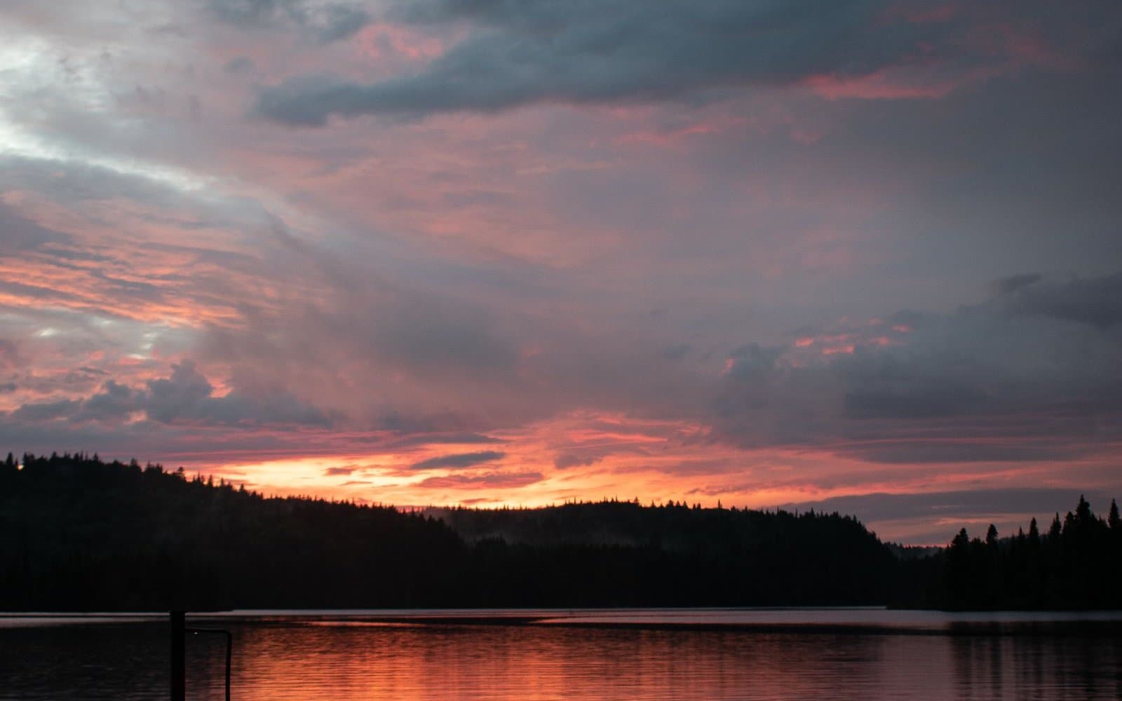 Mała łódź motorowa przy pomoście na spokojnym jeziorze o zachodzie słońca
