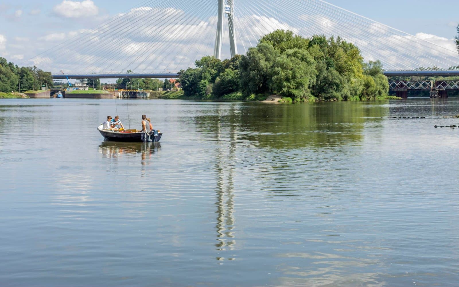 Motorówka z załogą na Odrze pod Wrocławiem, w tle most Rędziński i wrota śluzy