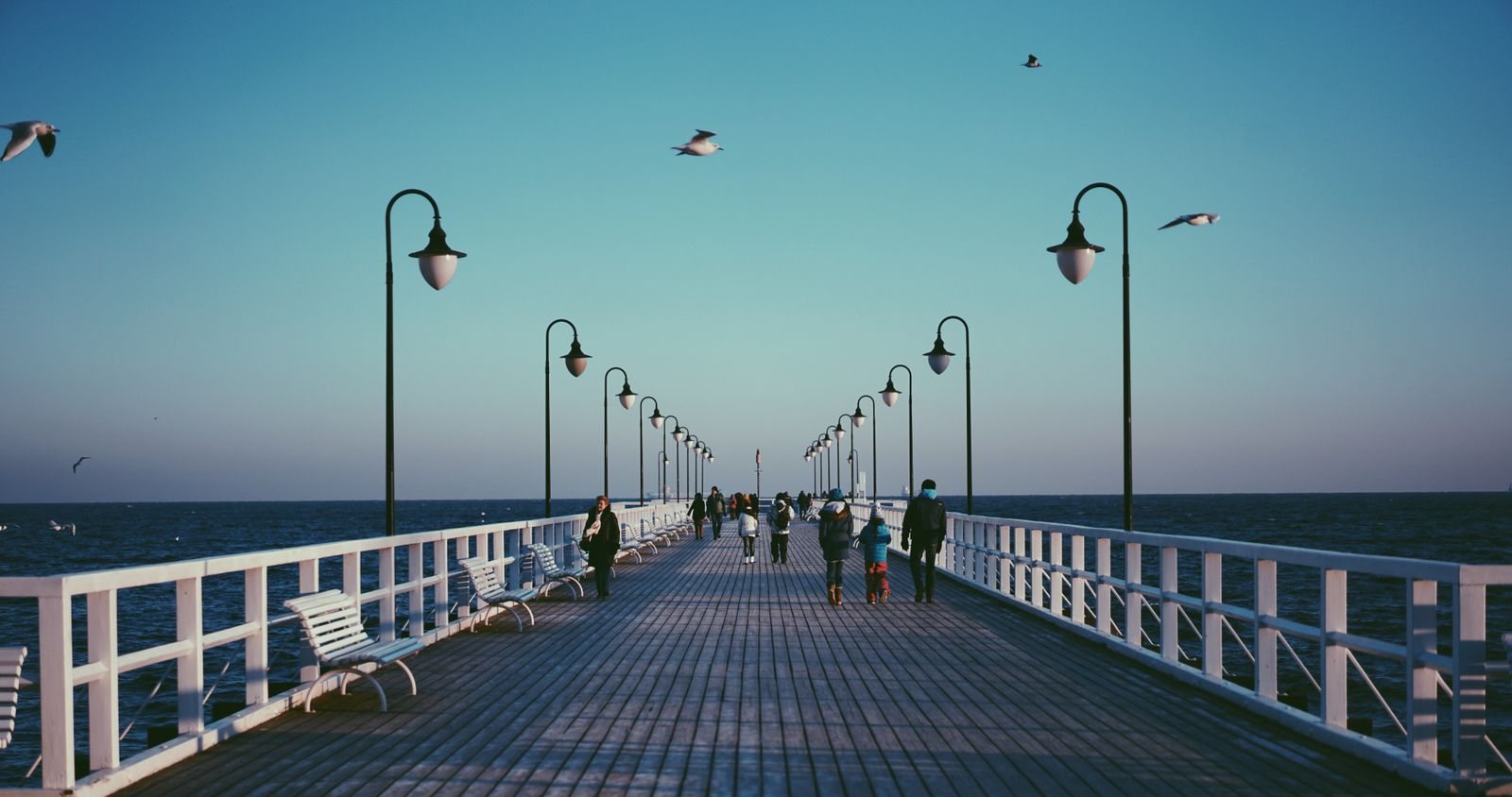 A wooden pier on the Gulf of Gdansk with strollers and lamps